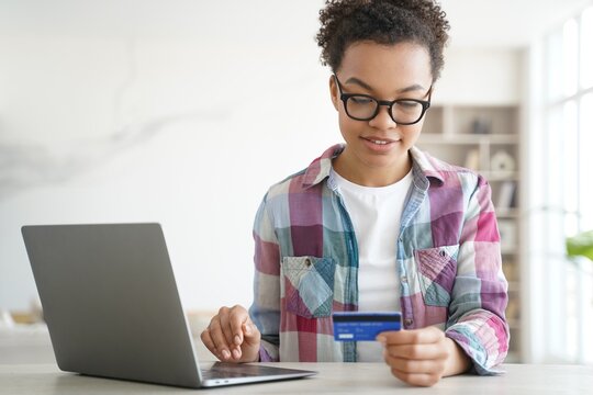 African American Teen Girl Holds Credit Bank Card Uses Banking Services Online On Laptop. E-commerce