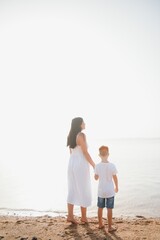 mother and son walking on sunset beach