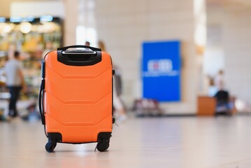 Large suitcase standing on the floor in modern airport terminal. Copy space