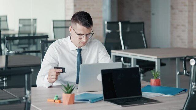 excited man hand gesture success businessman wearing white shirt and tie holding credit card using laptop sitting at the workplace in the office