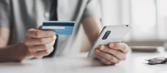 Man holding credit card and using smartphone at office panoramic banner, businessman shopping online, e-commerce, internet banking, spending money, working from home concept