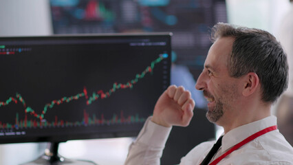 Close up male stock market broker celebrating with analyzing graphs on computer screen 
