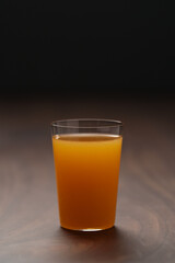Fresh orange juice in thin glass on wooden table with copy space