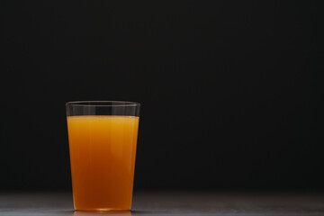 Fresh orange juice in thin glass on wooden table with copy space