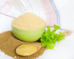 Dry mustard in a bowl, a spoonful of mustard seeds