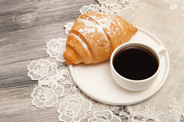 Croissant and coffee cup on saucer top view
