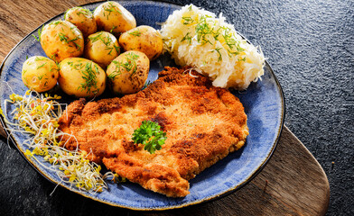 Pork cutlet coated with breadcrumbs with potatoes and cabbage