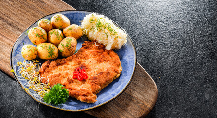 Pork cutlet coated with breadcrumbs with potatoes and cabbage