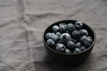 Freshly washed organic blueberries in a black bowl closeup