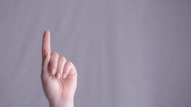 Close-up of a woman's hand counting to five with her fingers. Isolated on a grey background.