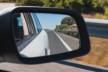 Road as seen from the rearview mirror of a car
