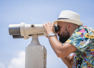 Man watching through binoculars telescope standing on observation point