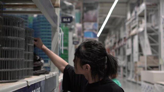 A modern Asian man chooses building materials in a hardware store