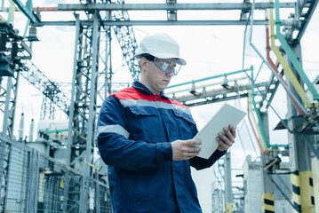 An energy engineer inspects the modern equipment of an electrical substation before commissioning. Energy and industry. Scheduled repair of electrical equipment.