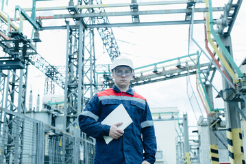 Fototapeta premium An energy engineer inspects the modern equipment of an electrical substation before commissioning. Energy and industry. Scheduled repair of electrical equipment.