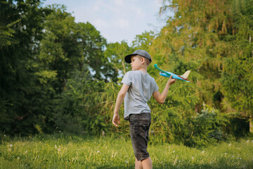 caucasian boy launching toy plane in park