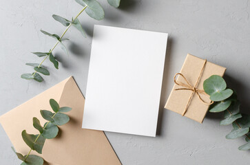 Greeting card mockup with gift, envelope and fresh eucalyptus twig