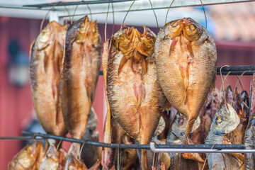 Hanging smoke-dried various fish in a fish market just smoked with hardwood wood chips in a smoker...