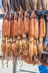 Hanging smoke-dried calamari or cuttlefish in a fish market just smoked with hardwood wood chips in a smoker and ready to eat, vertical