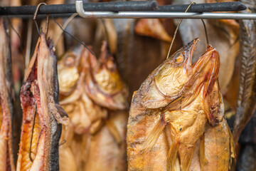 Hanging smoke-dried various fish in a fish market just smoked with hardwood wood chips in a smoker...