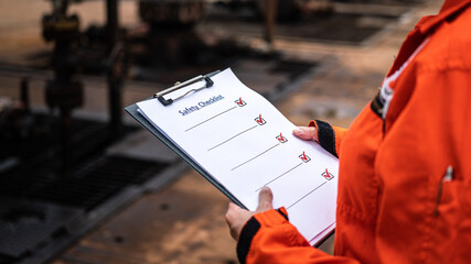A blank safety checklist form on safety officer or operation supervisor hand, preparing to perform...