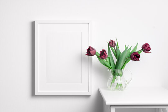 Vertical picture frame mockup on white wall with spring tulips flowers