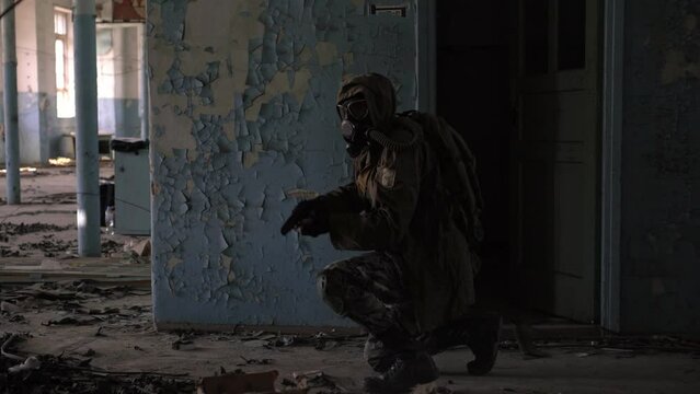 A soldier in a gas mask with a weapon in the building. Military man or stalker in destroyed house, post apocalypse survival concept