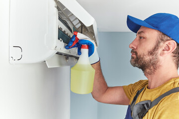 Repairman cleaning and fixing indoors AC unit.