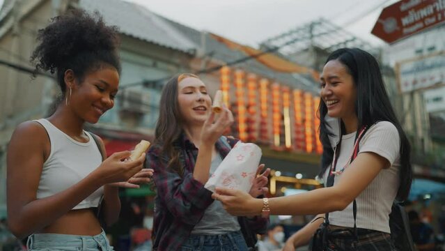 Group of beautiful young ladies travel at city. They eating local food together. Slow motion shot.