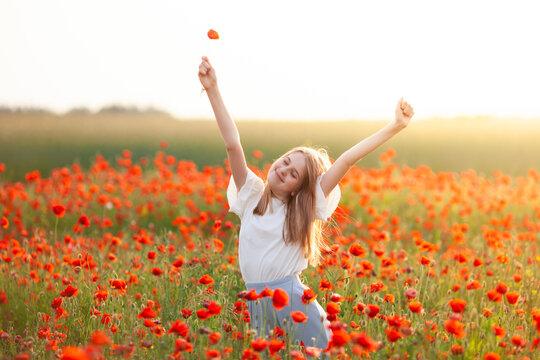 Blond girl stretching in the poppy field at sunrise. Start new day with happy smile. Unity with nature, natural cosmetics, good morning, relaxation, freedom and happiness concept. - Powered by Adobe