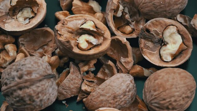 Lot of walnuts in the shell are spinning on a black background. Nuts are good for the brain. Heap of walnuts close-up.