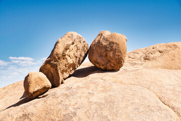 Fototapeta na wymiar Three big rocks leaning against each other, looking like toys and defying gravity. Impressive nature scene in Spitzkoppe National Park, Namibia. 