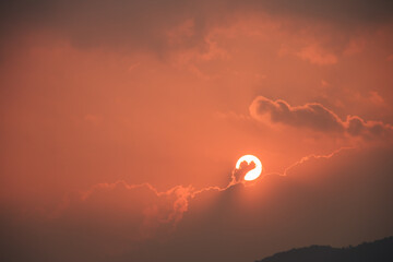 Dramatic fiery red sunset sky with a white sun and dark clouds. Fantastic, magical, fantasy scene. End of the world.