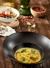 Traditional georgian dish - sacivi with chicken and walnut sauce. Roasted chicken in walnut sauce on black plate. Georgian food on wooden background. Meat appetizer in rustic style on wood table.