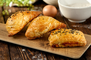 aditional uzbek pastry - samsa with meat. Uzbek pies with meat and puff dough on wooden background in rustic style. Meat samosa with ingredients. East pastry.