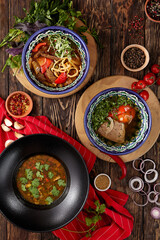 Traditional eastern soups: kharcho, lagman, shourpa on wooden background. Composition of meat soup in rustic style. Set of georgian soup kharcho, uzbek shourpa and lagman with noodles.