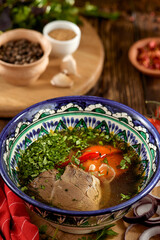 Eastern food - soup shourpa with vegetables and lamb meat on wooden table. Traditional uzbek soup with lamb meat, sweet pepper, tomatoes in rustic style. Caucasian cuisine on dark wooden background.