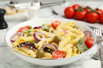 Bowl of delicious pasta with tomatoes, olives and onion on white marble table, closeup