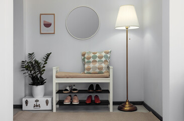 Stylish hallway room interior with bench, shoes and round mirror