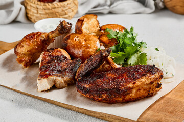 Roasted chicken with spices and herbs on wooden plate. Traditional caucasian food - chicken tabaka. Grilled chicken with bread and sauce on concrete background.