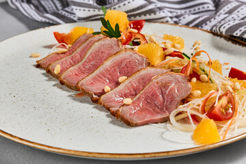 Healthy salad with duck meat, orange and vegetables. Chinese food - duck salad with citrus and fresh dressing. Sliced duck meat with crispy vegetables and pine nuts.