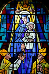 Stained glass depicting a crowned Virgin and child giving a rosary to a bishop
