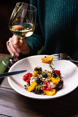 Fried Camembert cheese with cherry tomatoes, capers and basil. Baked Camembert or brie cheese with tomatoes on black background. Gourmet traditional Breakfast. Selective focus.