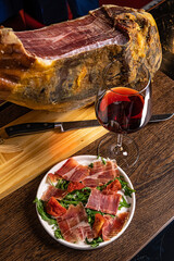 Iberian ham pata negra from Spain with red wine on wood background - obrazy, fototapety, plakaty