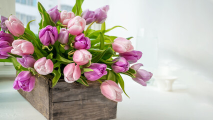 Multicolored tulips in a wooden textured box, selective focus, copy space