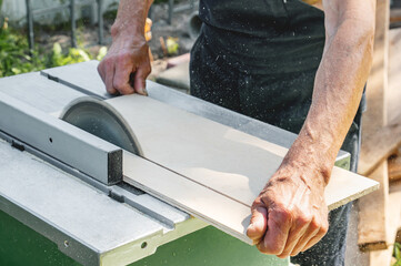 turner works on a lathe. Close-up. saw table. a man saws a tree with a milling machine. An experienced carpenter cuts a wooden board with a circular saw. Production of wood materials. Real life