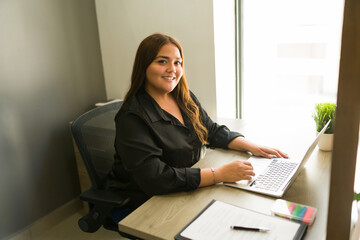 Beautiful woman typing on the laptop at her desk