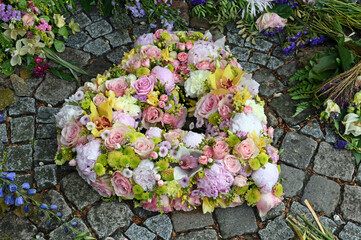 Grabgesteck in Herzform mit rosa, gelben und weißen Blüten