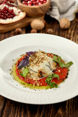 Hot appetizer - baked eggplant with cheese and tomatoes. Stuffed eggplants with mozzarella cheese and tomato sauce in rustic style. Eggplant and cheese appetizer on white plate in italian style.
