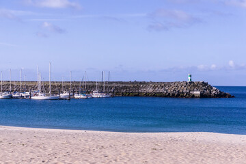 Breakwater with a lighthouse on it and moored yachts